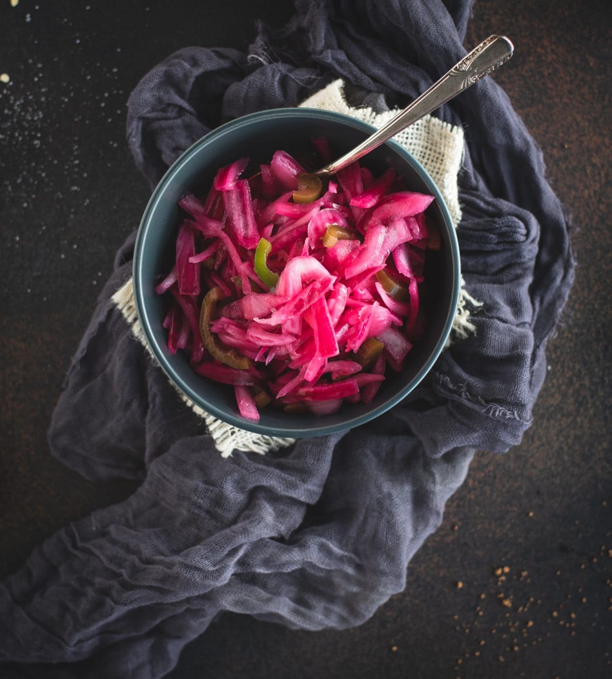 Overhead picture of bowl of pickled red onions on dark background