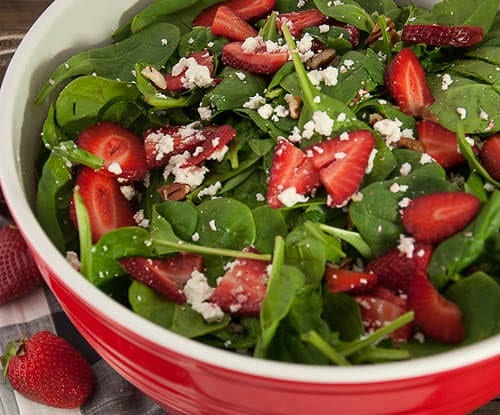 strawberry spinach salad in a red bowl