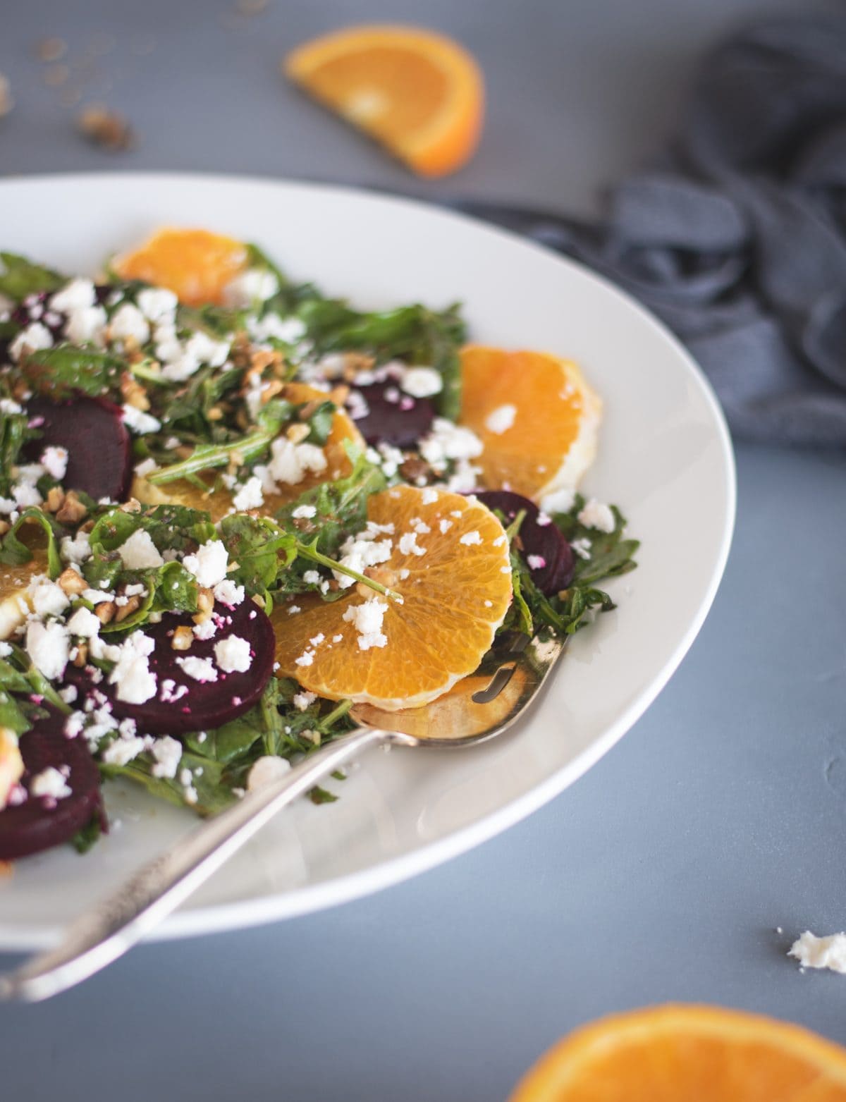 arugula salad on a white plate with beets and orange