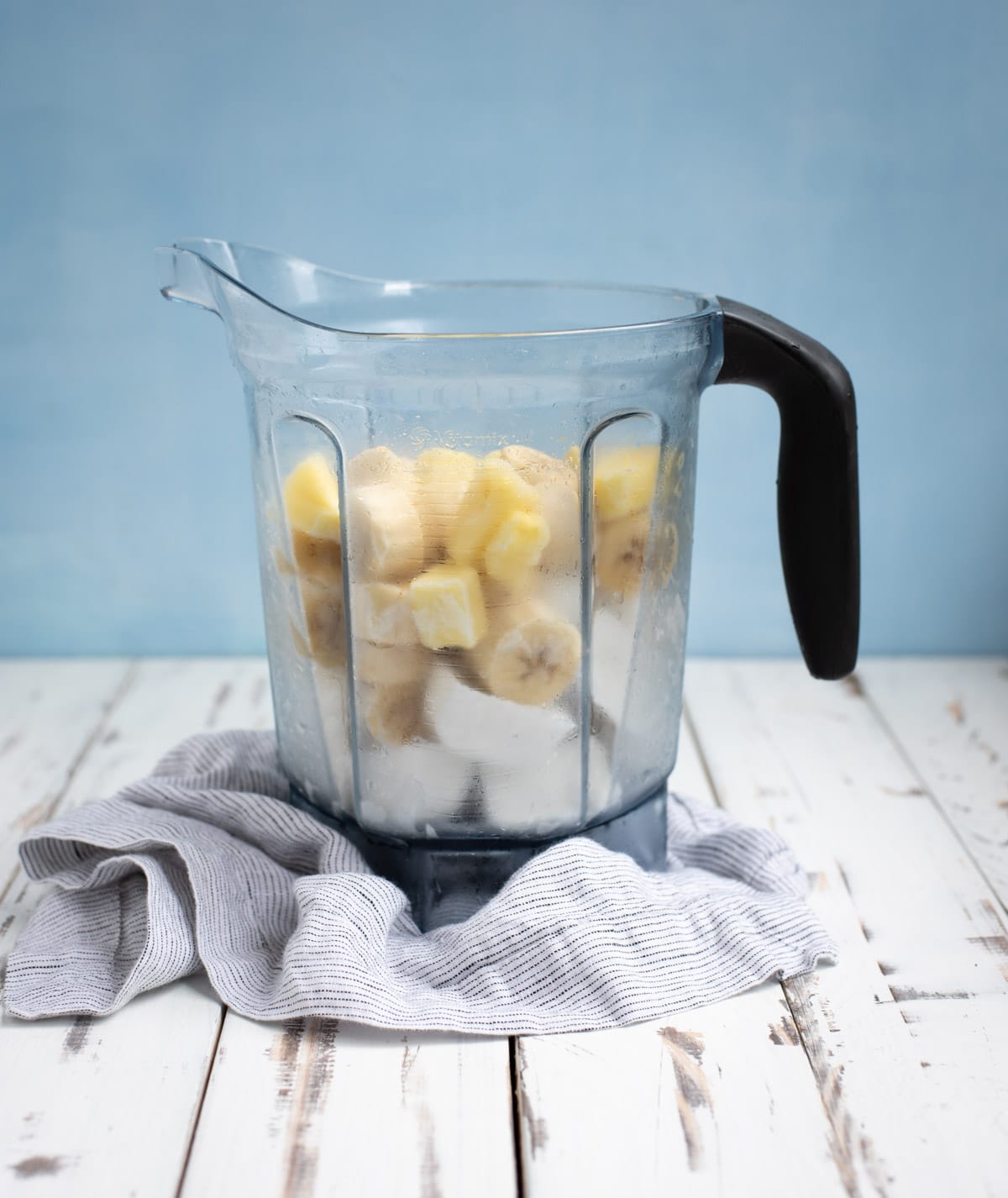 blender pitcher with banana ice cream ingredients before being blended