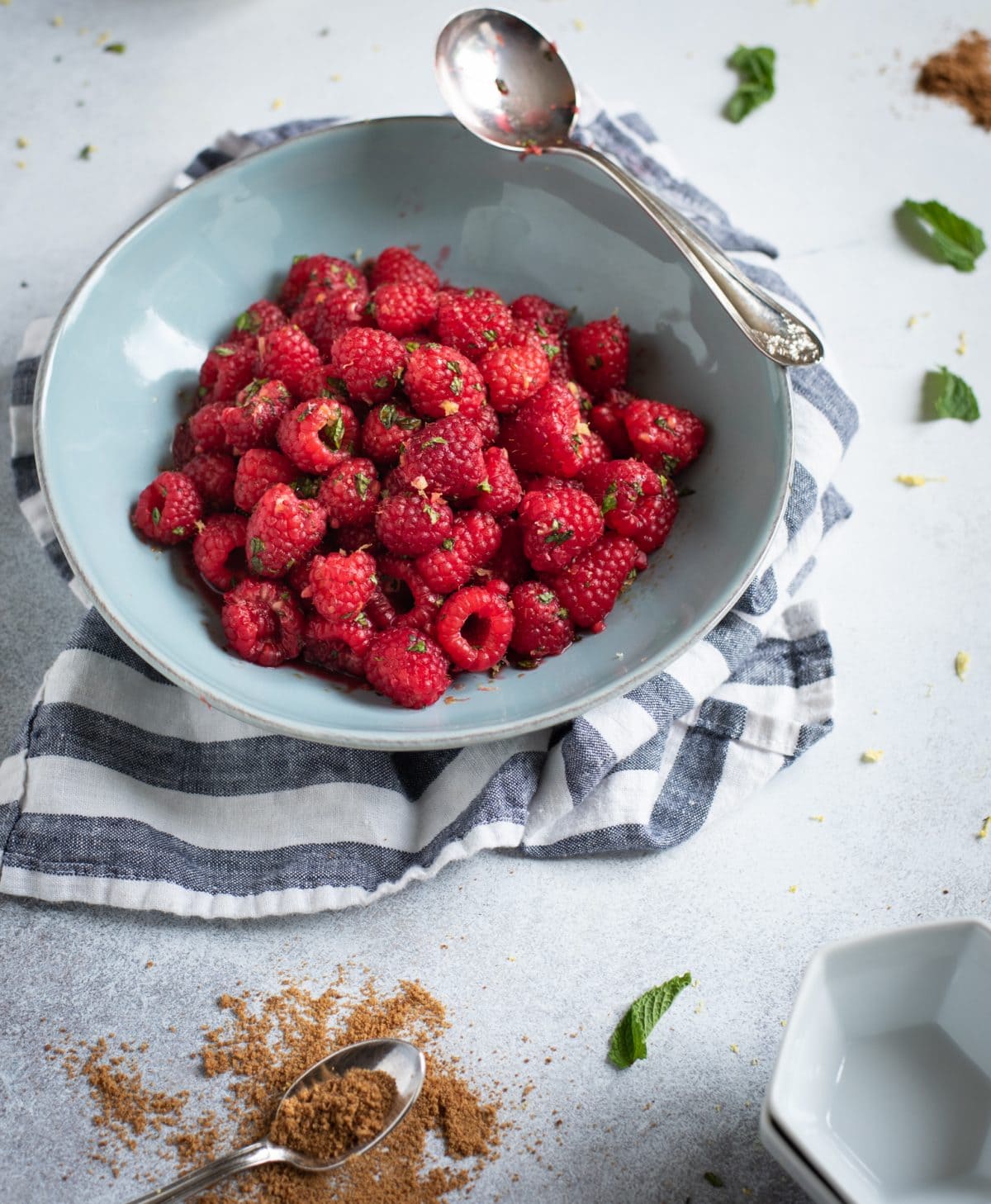 Photo of blue bowl full of Raspberries with lemon zest and mint