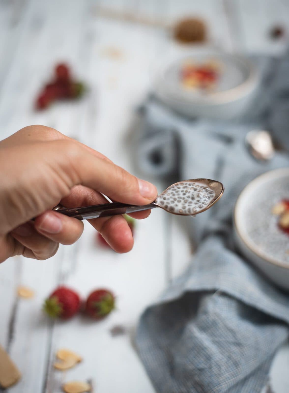 Almond chia seed pudding on a spoon held up by a hand