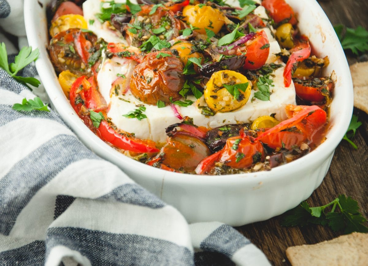 Baked feta with roasted vegetables in a white dish