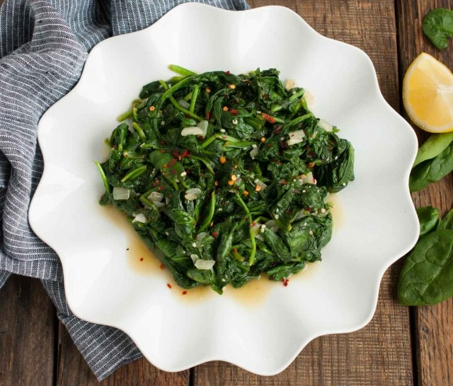 sauteed spinach overhead with lemon wedge and onion