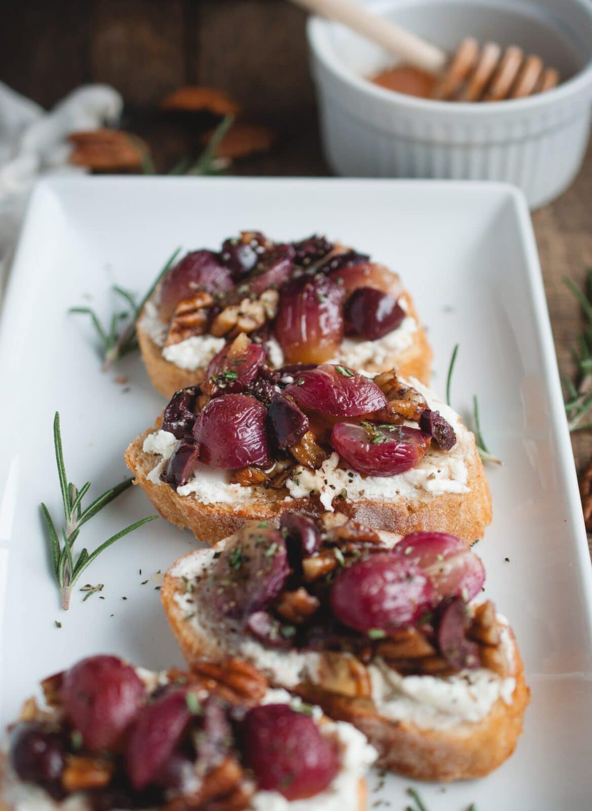 close up picture of plate with four pieces of appetizer Crostini with Roasted Grapes