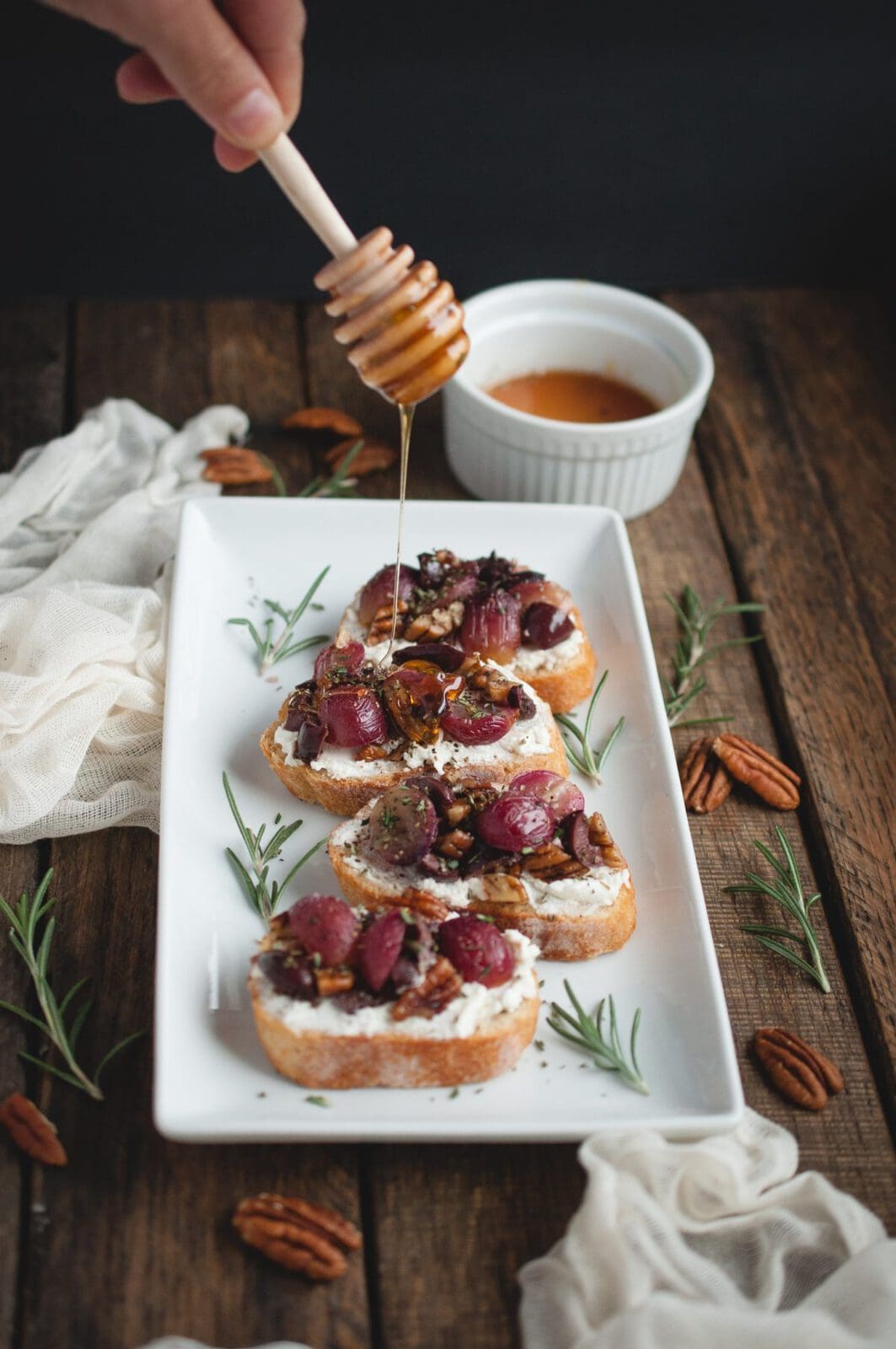 Hand drizzling honey over holiday Crostini 