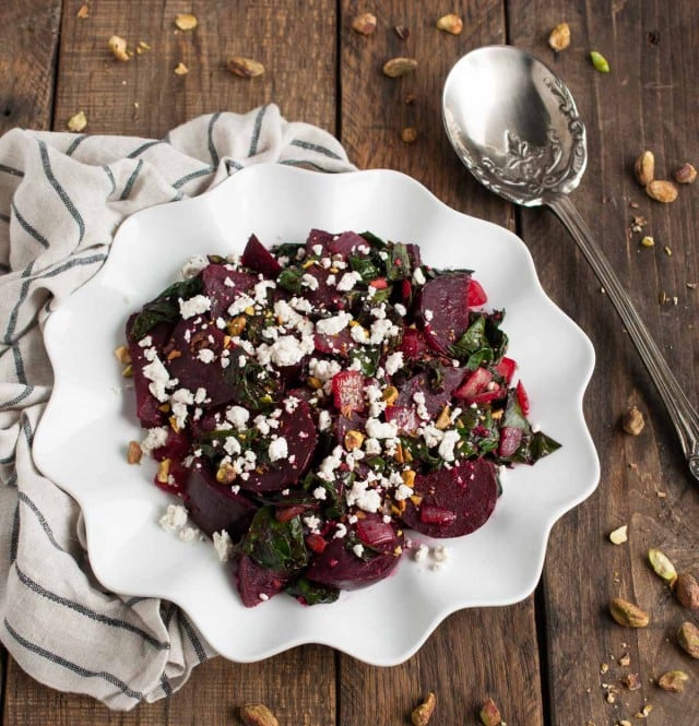 These light, delicious sautéed beet greens are tossed in tangy vinegar and spices before being topped with roasted beets, crushed pistachios, and crumbles of goat cheese.