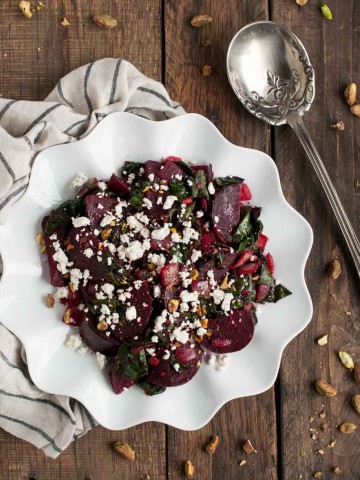 These light, delicious sautéed beet greens are tossed in tangy vinegar and spices before being topped with roasted beets, crushed pistachios, and crumbles of feta cheese.