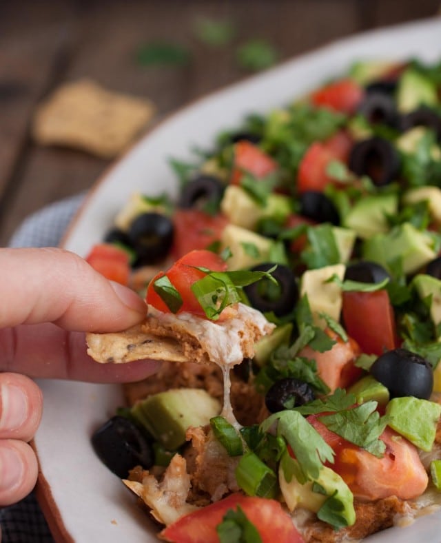 This Mexican bean dip is easy and tasty as can be with Greek yogurt adding a nutrition and protein punch. The melted cheese and toppings take it over the top!