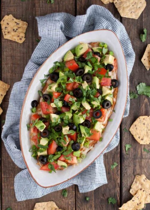 This Mexican bean dip is easy and tasty as can be with Greek yogurt adding a nutrition and protein punch. The melted cheese and toppings take it over the top!