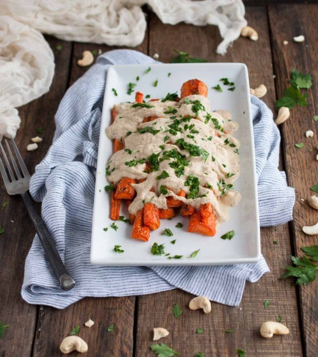 Cashew cream sauce is drizzled over perfectly roasted caramelized carrots in this easy, flavorful, absolutely delicious, naturally vegan dish.
