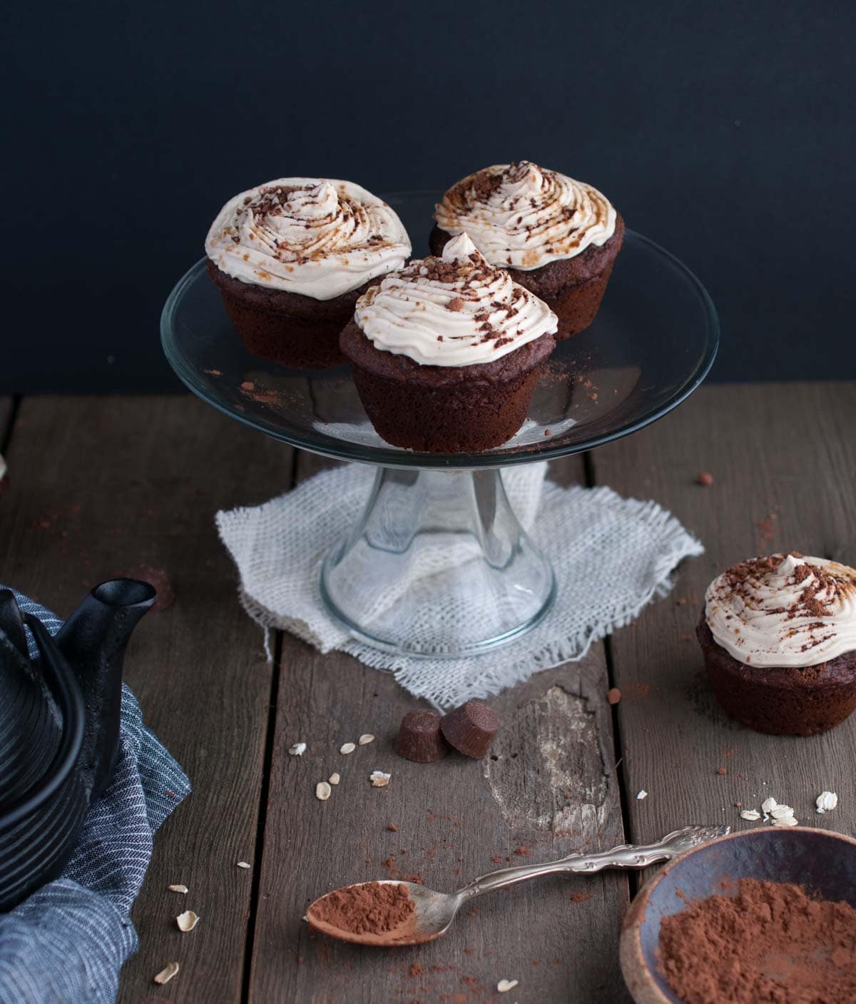 frosted chocolate cupcakes with peanut butter cups on a stand of cupcakes against a dark background