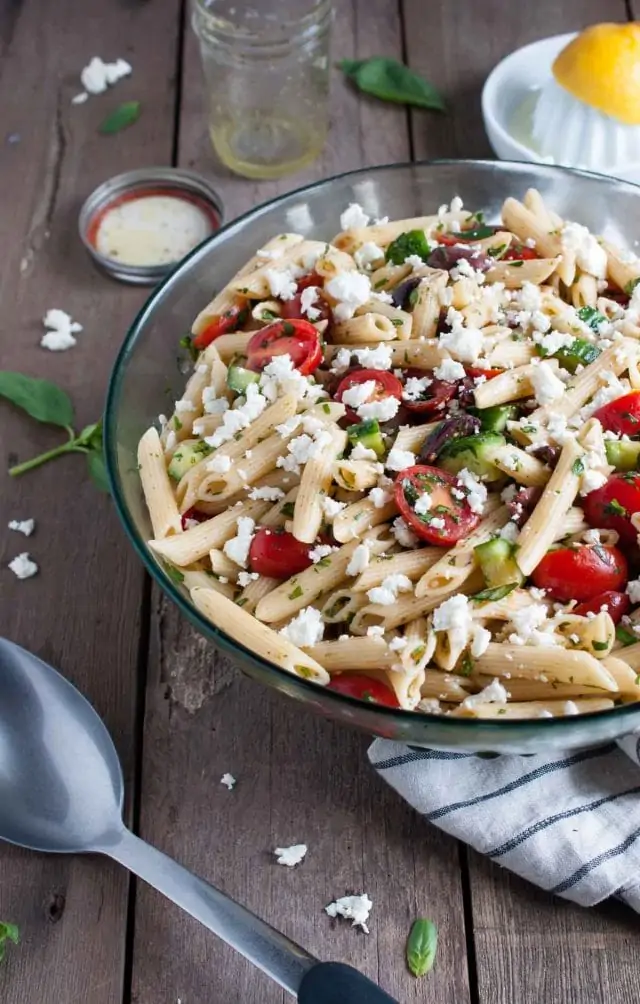 Greek pasta salad with juicy tomatoes, crunchy cucumbers, fresh herbs, olives and other goodies, all tossed in a tangy lemon vinaigrette.