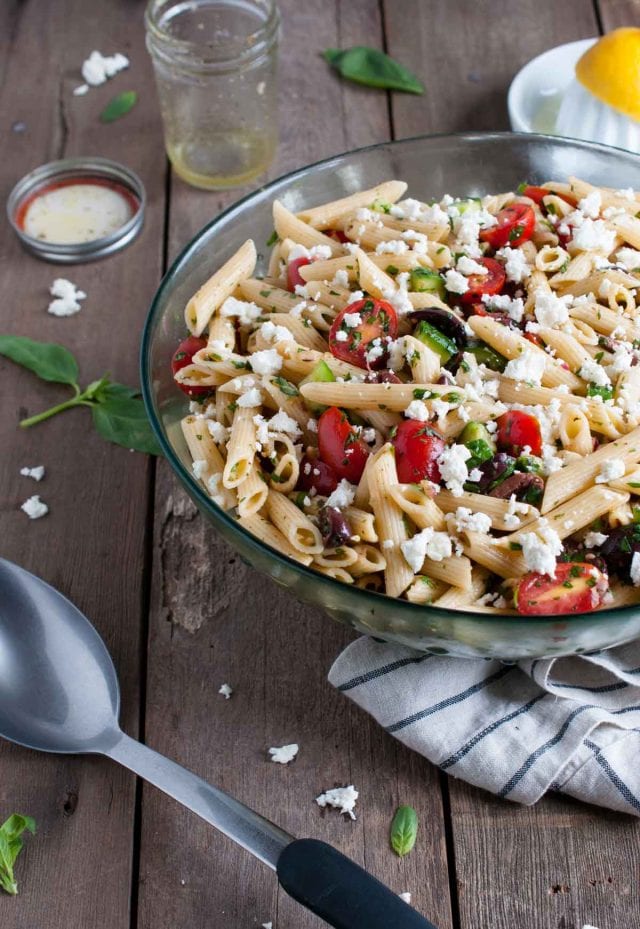 Greek pasta salad with juicy tomatoes, crunchy cucumbers, fresh herbs, olives and other goodies, all tossed in a tangy lemon vinaigrette.