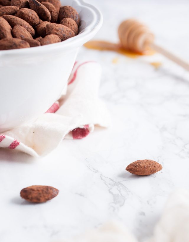 cocoa dusted almond on a marble countertop by a bowl of cooca almonds