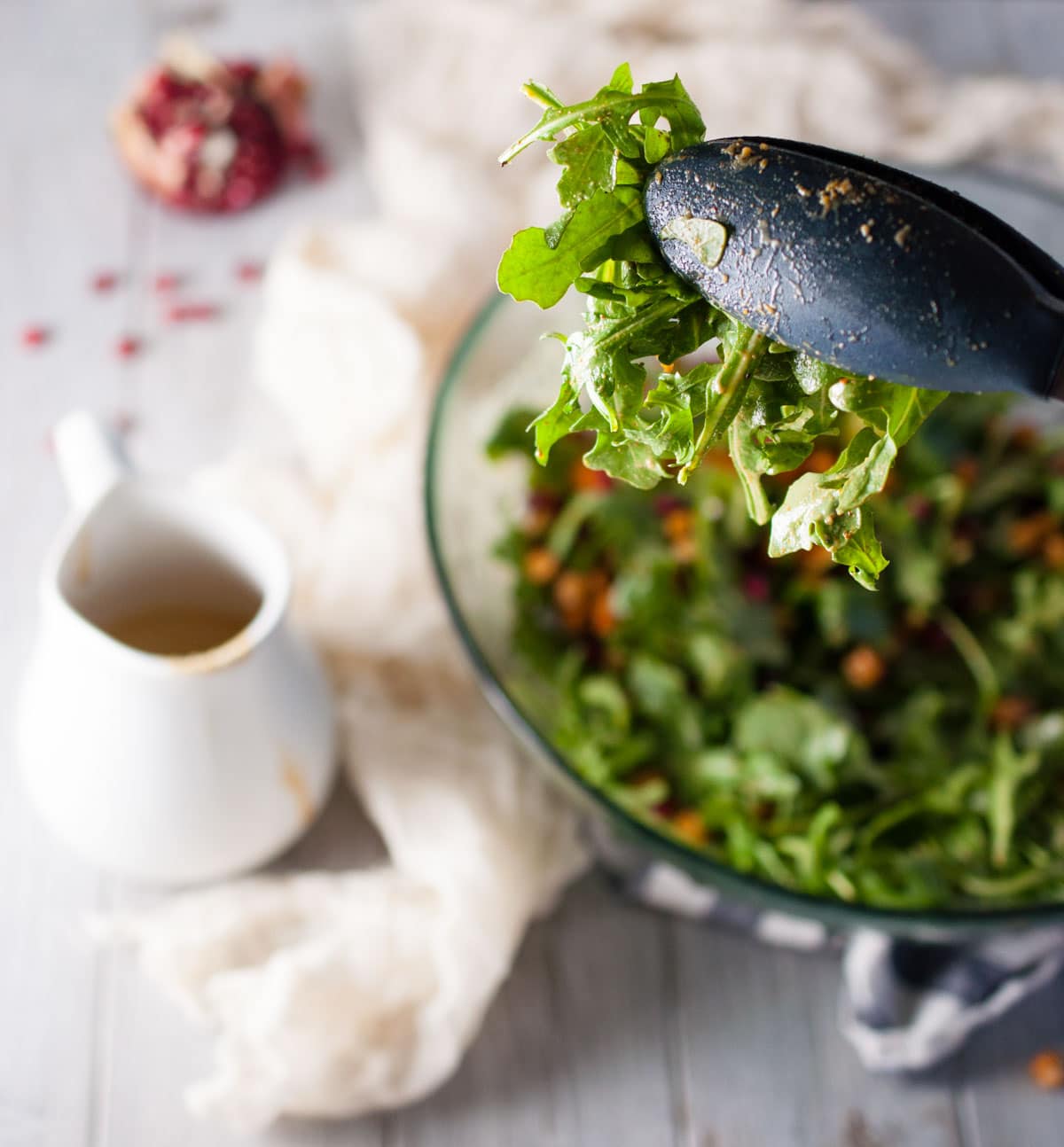 Tasty arugula sweet potato salad with zesty yet creamy tahini dressing, crunchy roasted chickpeas, and a pop of tartness from juicy pomegranate arils.