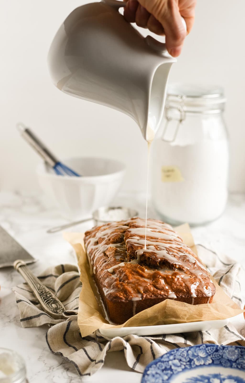 banana bread with glaze being drizzled on top