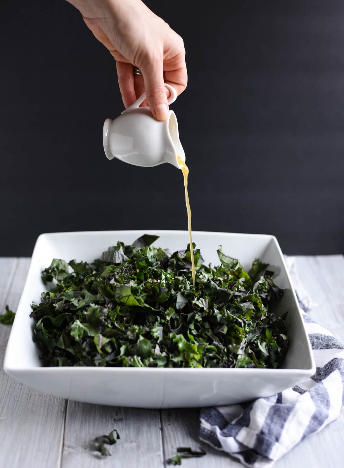 Dressing being drizzled onto kale salad