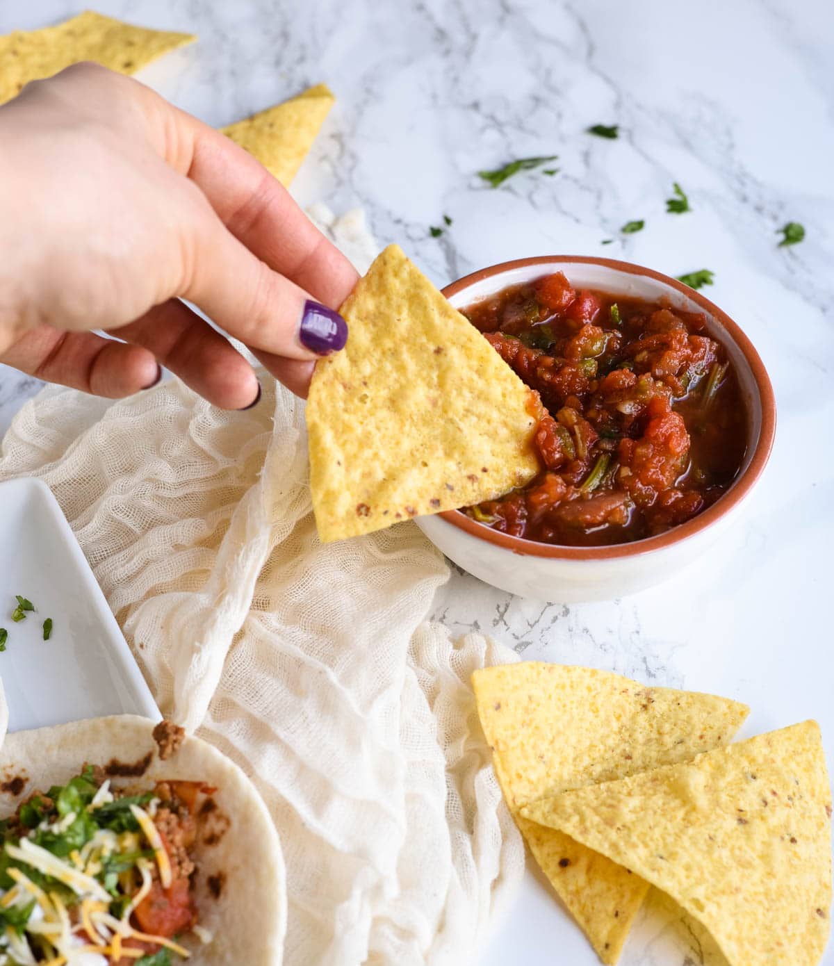 hand dipping chip into salsa