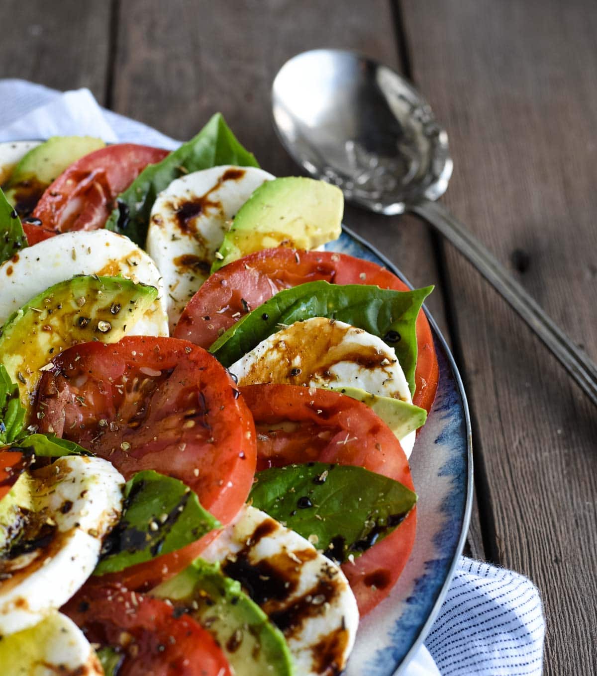 avocado caprese salad picture close up with tomato, mozzarella, basil, and balsamic 