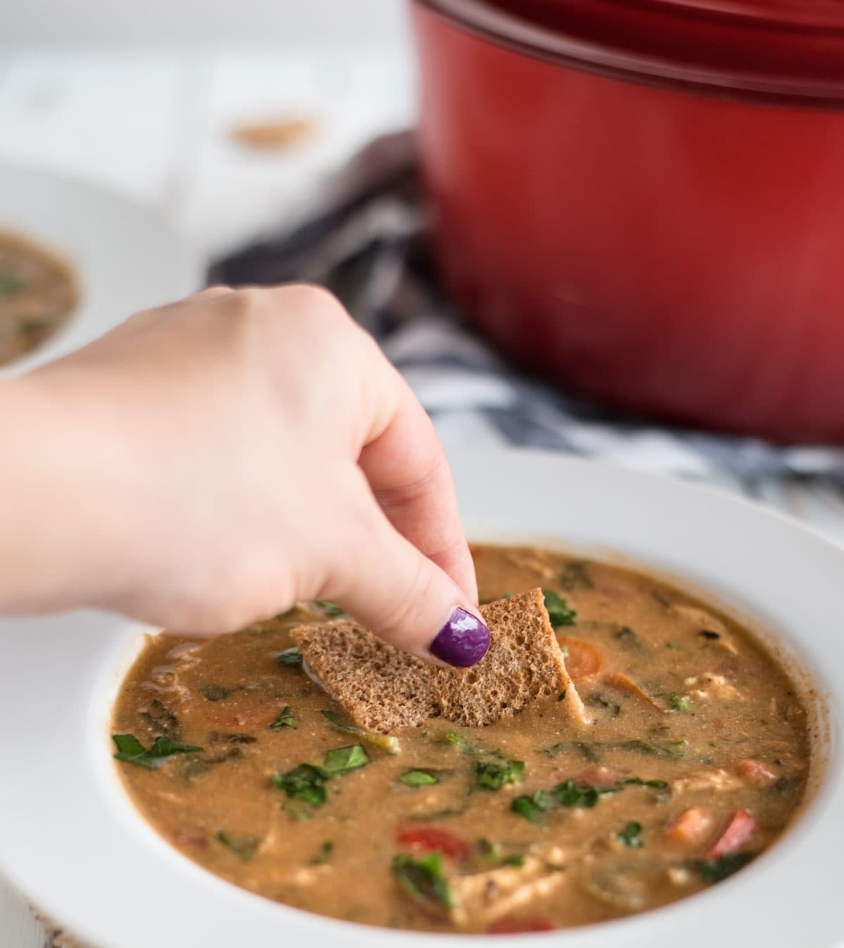 Hand dipping cracker into soup