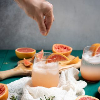 Hand sprinkling salt in Rosemary grapefruit mocktail