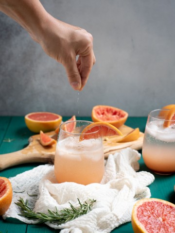 Hand sprinkling salt in Rosemary grapefruit mocktail