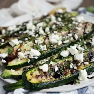 Picture of grilled zucchini on a plate with feta, basil and balsamic glaze