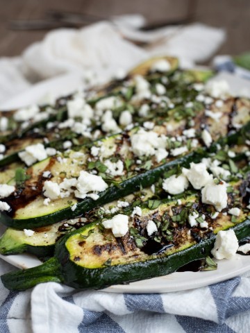 Picture of grilled zucchini on a plate with feta, basil and balsamic glaze