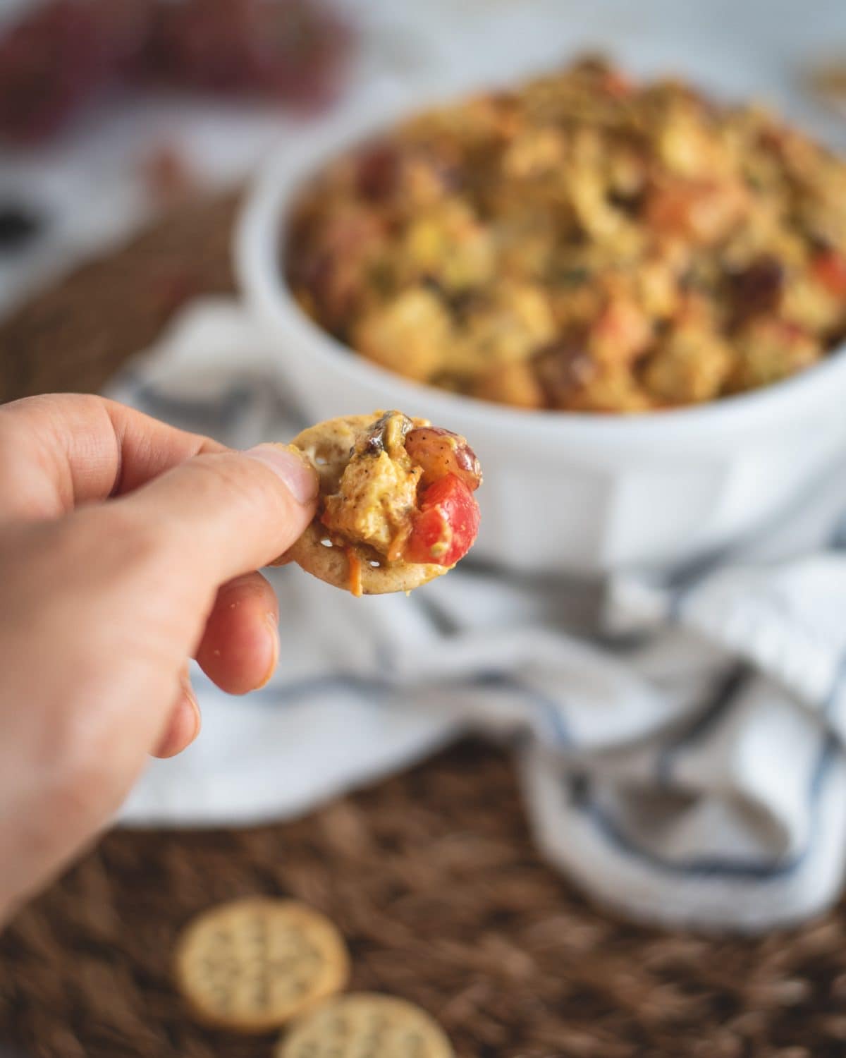 Picture of hand holding cracker with curry chicken salad on it