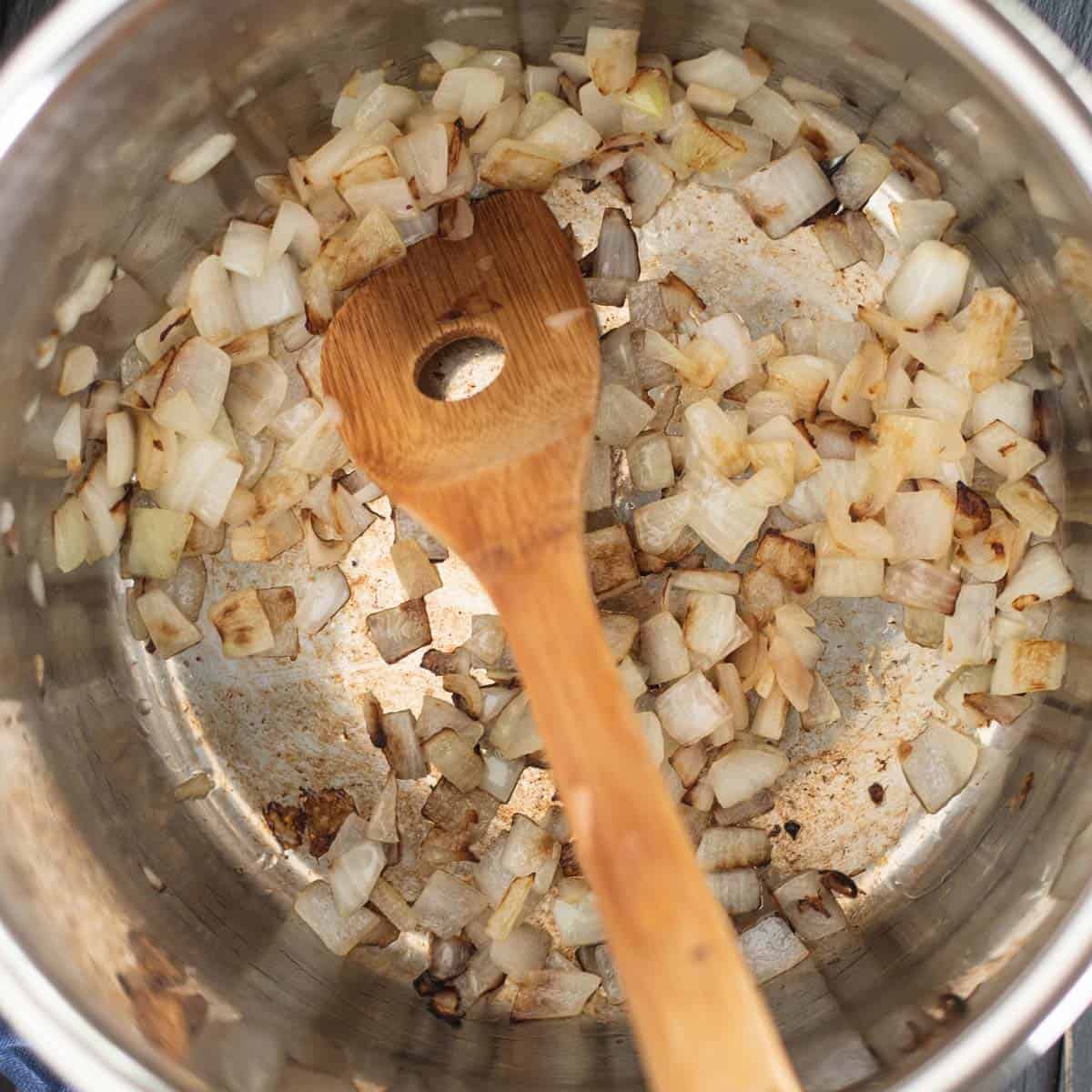 onions being sautéed in the bottom of an instant pot