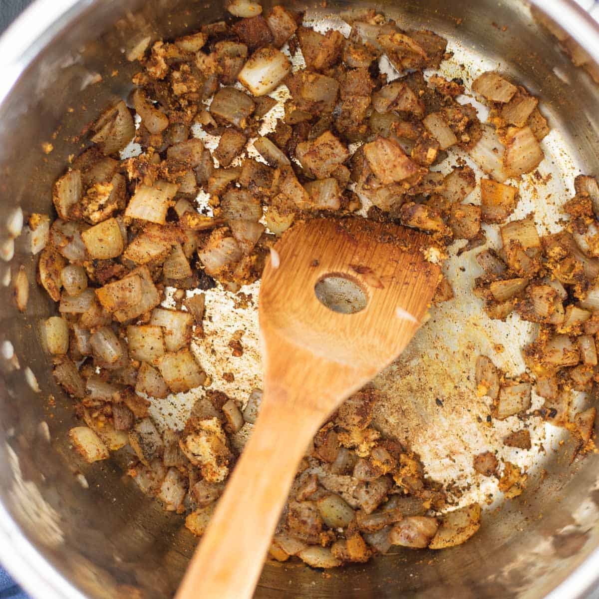spices being sauteed with chopped onion in an instant pot