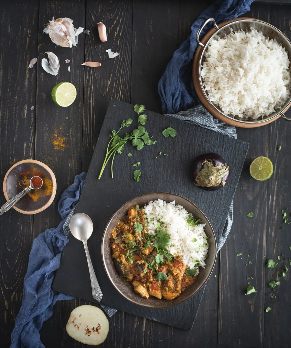 Overhead picture of Instant Pot chicken curry with eggplant with ingredients on dark background
