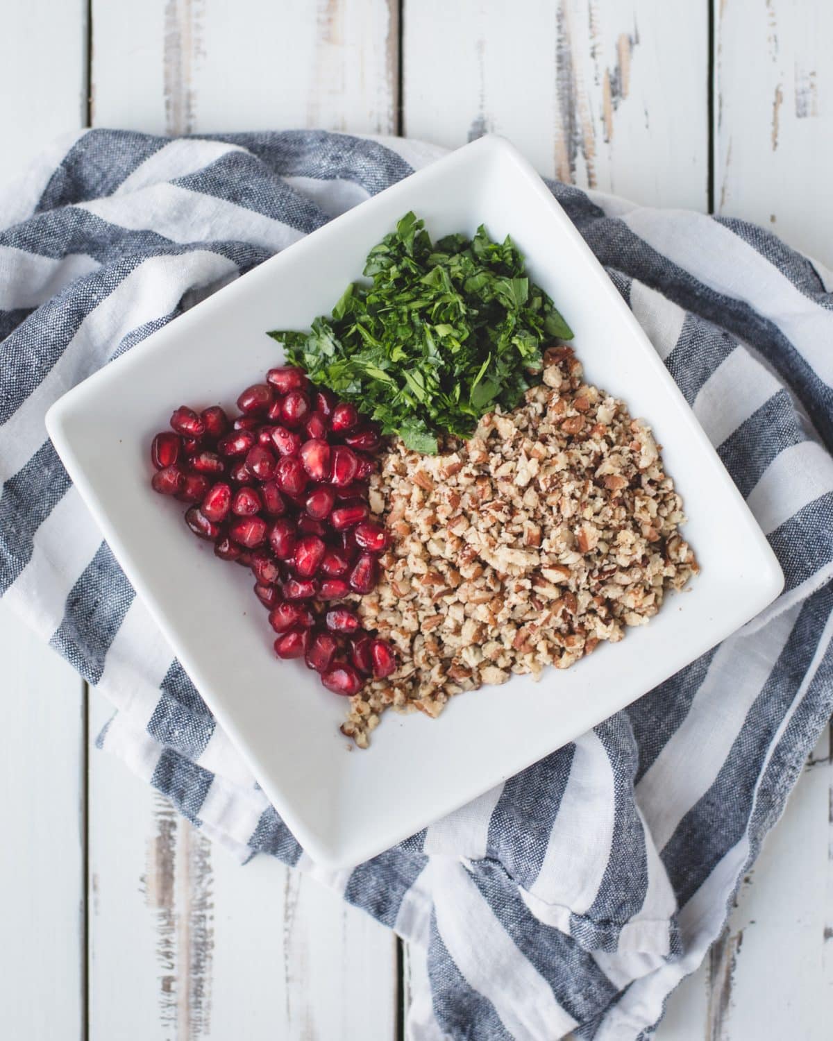 pomegranate, parsley, and crushed pecans in a white bowl