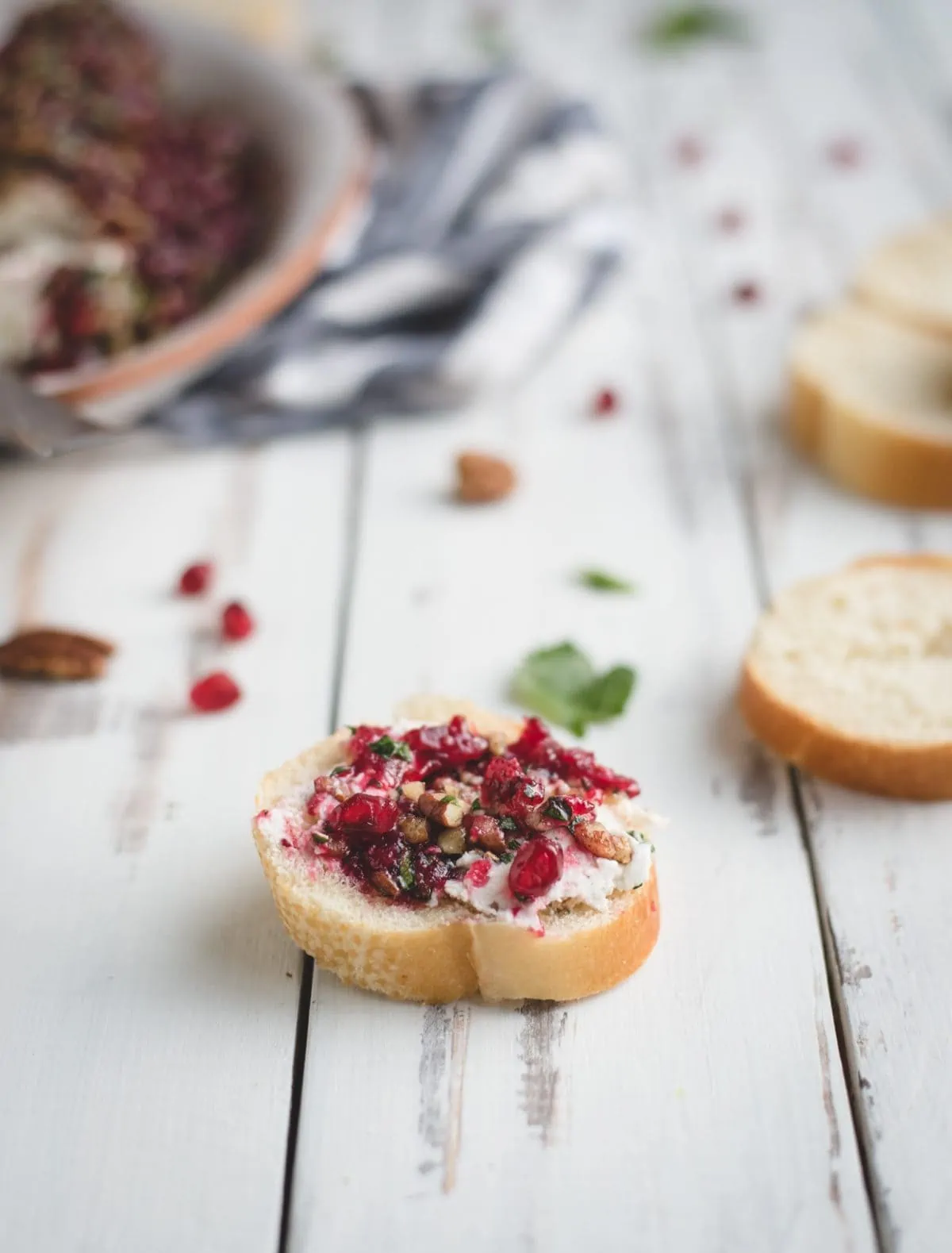 cranberry herb goat cheese log spread on a baguette slice