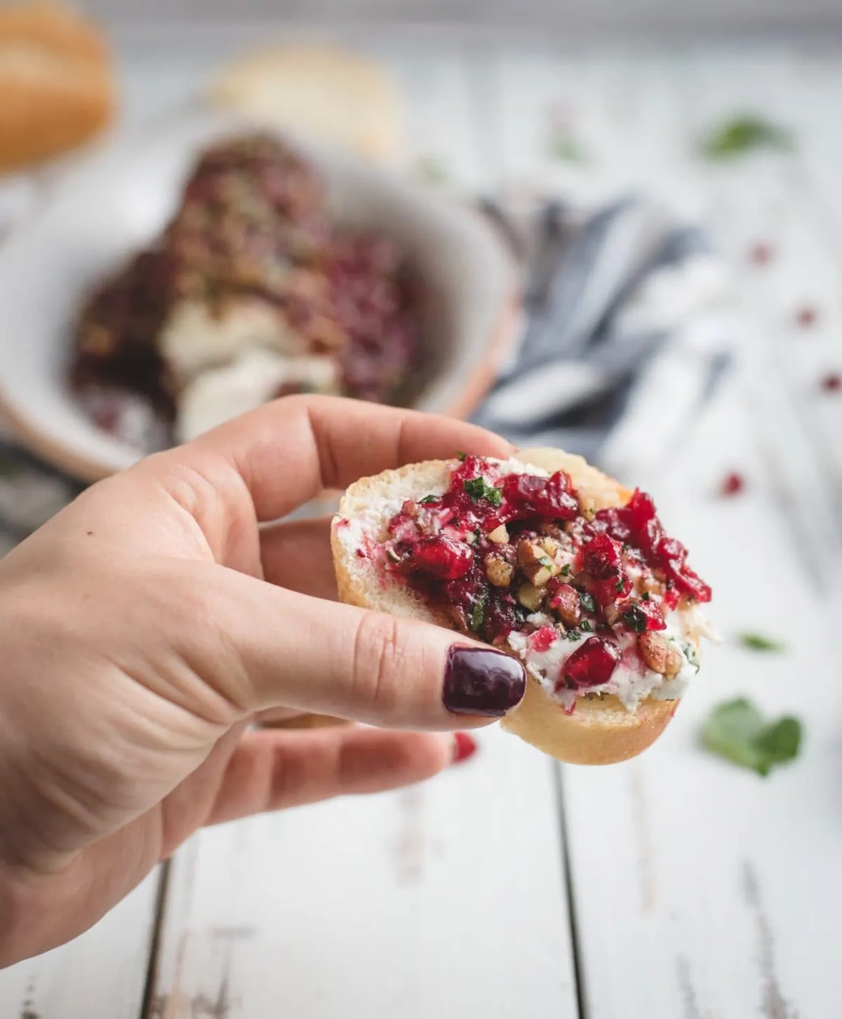 picture of hand holding cranberry herb goat cheese log on bread 