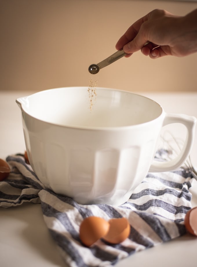 pepper being poured into a white mixing bowl