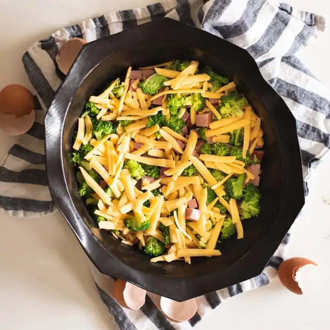 silicone pan with ham, broccoli, and cheese on blue and white kitchen towel