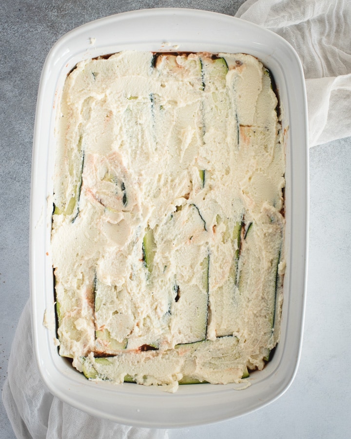 baking dish with zucchini and ricotta smeared on top