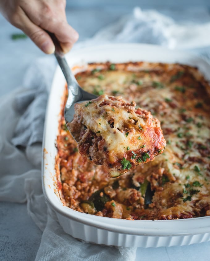 hand serving slice of zucchini lasagna