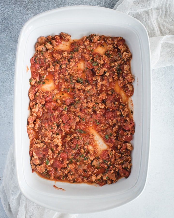 baking dish with layer of red sauce