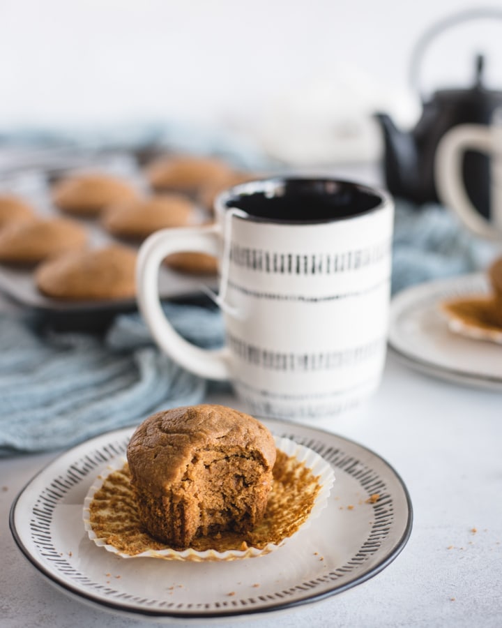 Healthy pumpkin muffin and cup of tea on white background with muffins in background