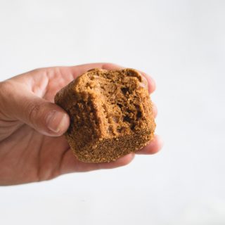 Close up picture of hand holding pumpkin muffin against white background