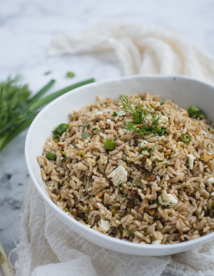 Side shot close up photo of brown rice side dish in white bowl on white background