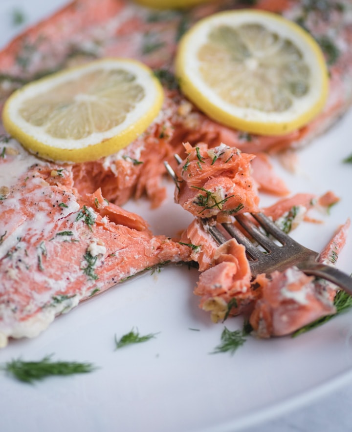 Close up picture of fork with flaked salmon with lemon and dill