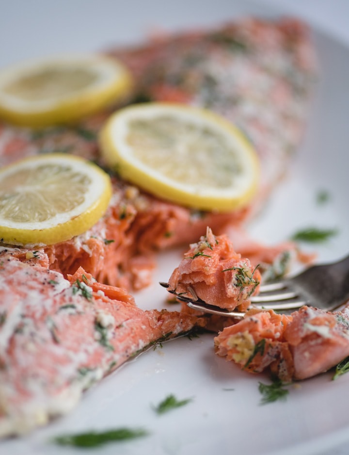 Bite of oven baked salmon with lemon and dill on a fork