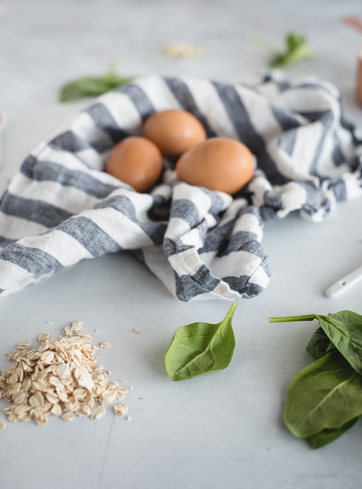 ingredients for spinach pancakes on light background