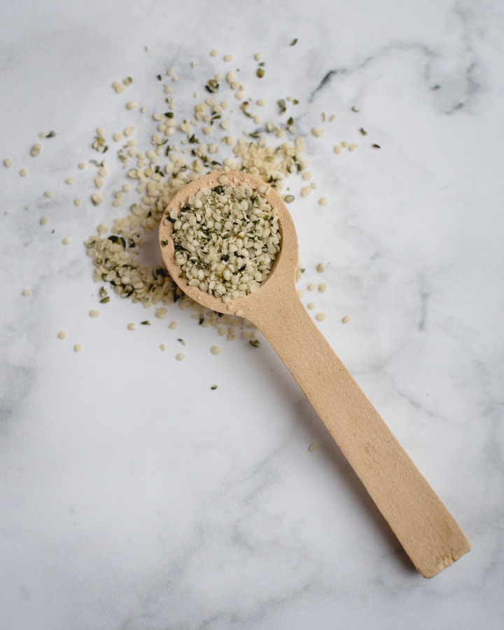 hemp hearts in a wooden spoon on white marble background