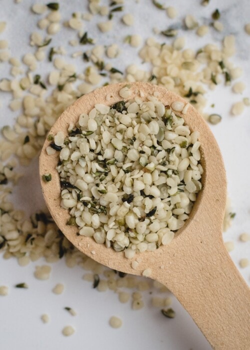 close up picture of wooden spoon with hemp hearts on white background