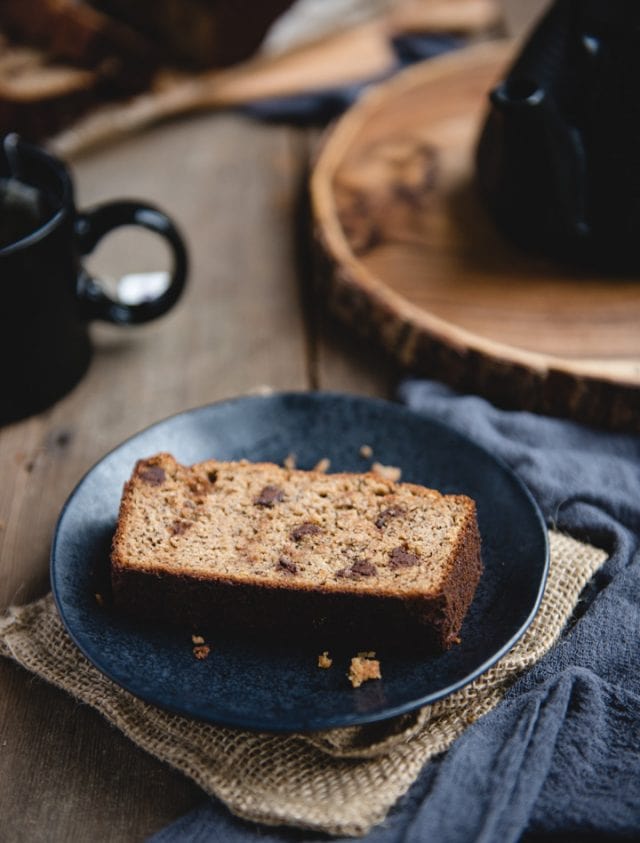 slice of banana bread on a dark plate and wood background